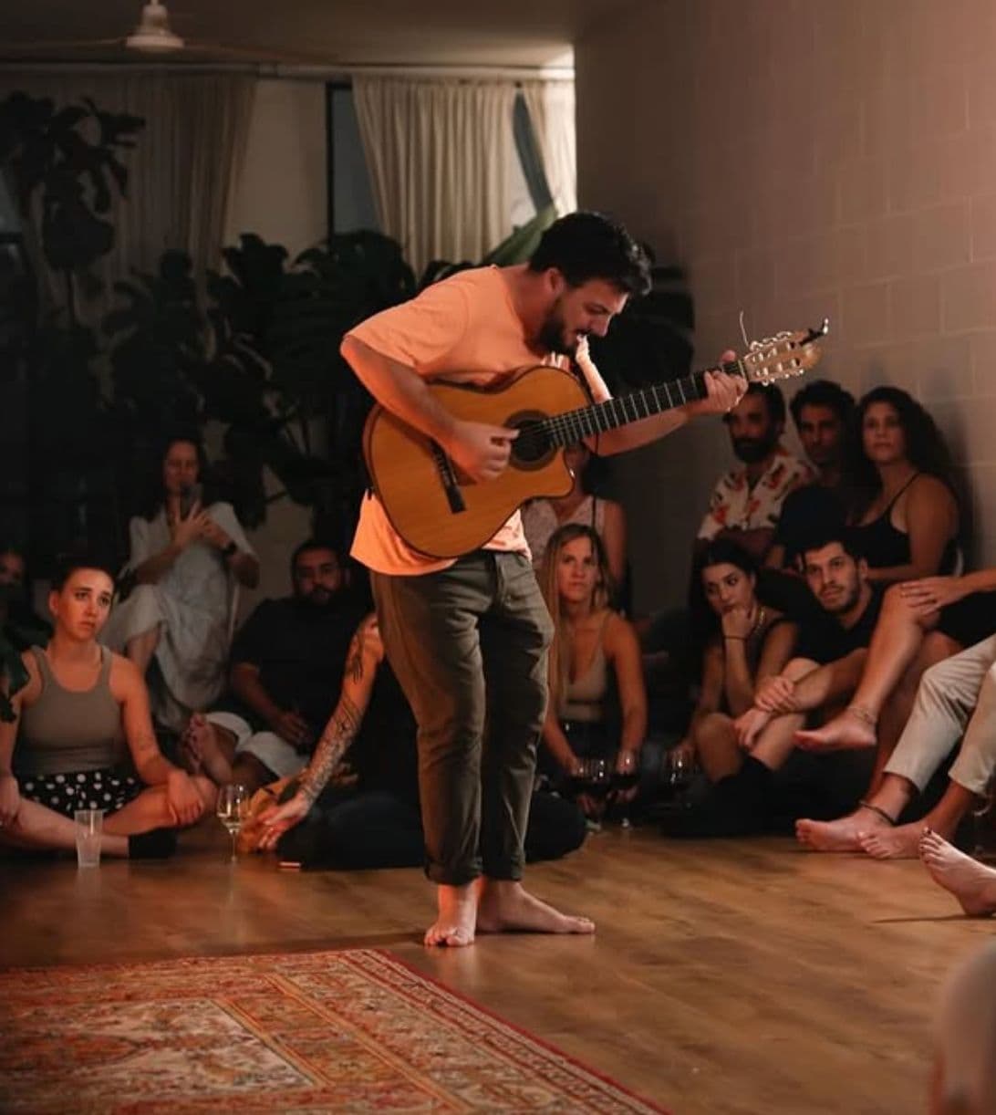 Rafa tocando descalzo rodeado de gente sentada en el piso