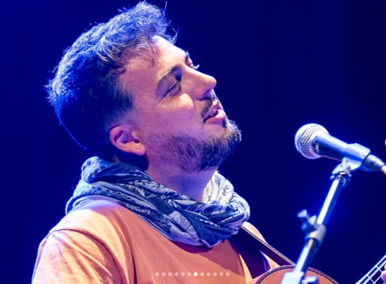 Primer plano de Rafa cantando al micrófono bajo luz azul