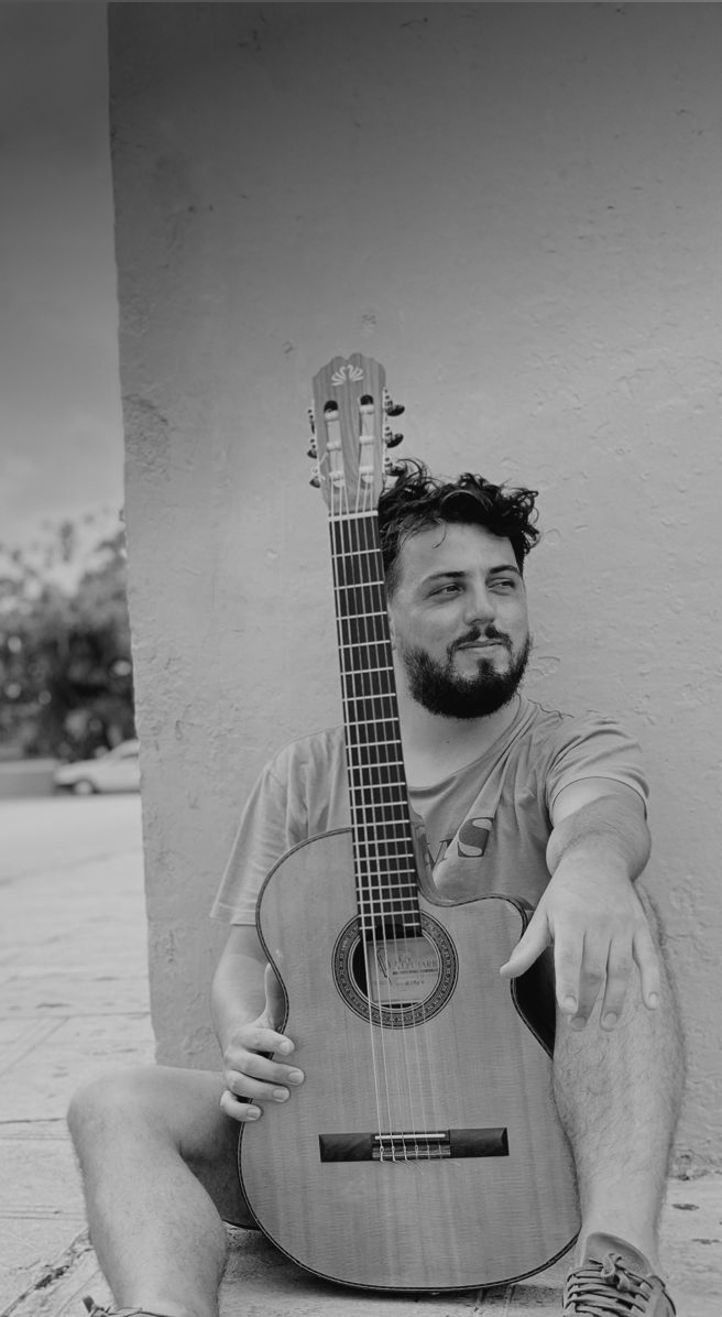 Rafa Doorish sentado en la vereda con su guitarra